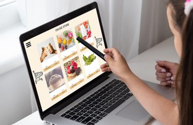 Close up woman sitting and ordering food online on laptop computer in add to cart function webpage.